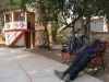 a giant sleeping on a small bench in a small Chilean town