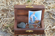 Wooden box containing a heart-shaped stone, a pendant with Virgin Mary, a cross, and a catholic oration.